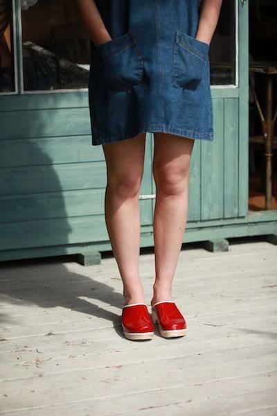 Wearing Patent Red women's Clogs with a white trim and natural wooden base by Lotta from Stockholm
