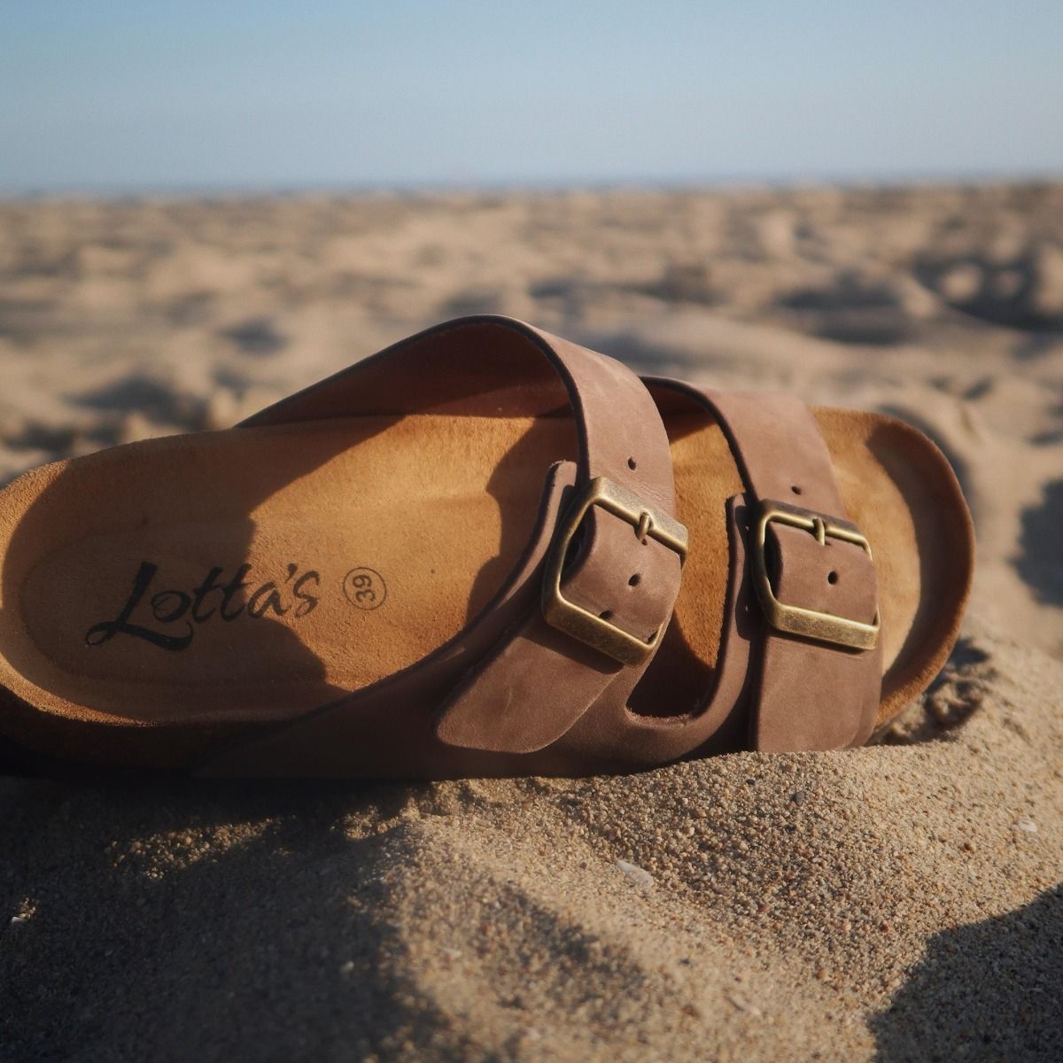 Lotta's Summer Cork Sandals in brown with leather uppers, soft suede insole, nickel free metal buckles and anatomically shaped cork footbed by Lotta from Stockholm. Shown here on the beach